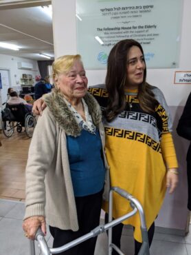 Two women standing next to each other in the Fellowship House for the Elderly.