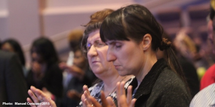 Two women lifting their hands up in praise as they pray.