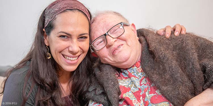 Yael Eckstein smiling & holding elderly disabled woman named Lydia